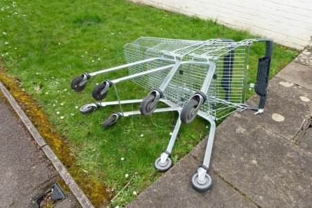 A Abandoned Shopping Trolleys on a Grass Verge in a Town on their Side Next To A Path
