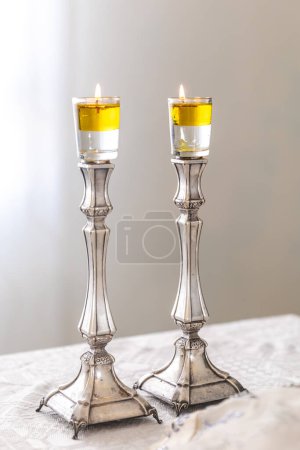 Photo for A pair of Shabbat candles are lit with oil on silver candlesticks on the Shabbat table. - Royalty Free Image