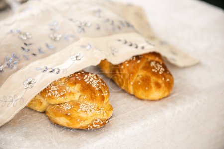 Photo for Homemade Challah bread with white cover, Jewish cuisine. Decorated with sesame. on the shabbat table - Royalty Free Image