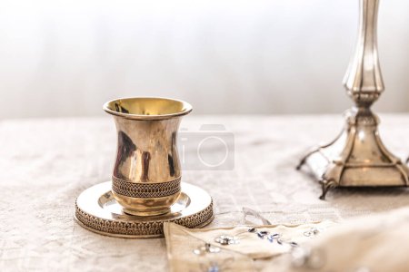 Photo for Traditional, decorative Jewish kiddush cup. Silver cup with saucer filled to the brim with purple wine isolated on a Shabbat table - Royalty Free Image