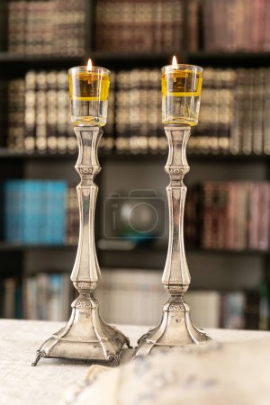 Photo for A pair of Shabbat candles are lit with oil on silver candlesticks on the Shabbat table. - Royalty Free Image