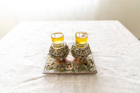 Photo for A pair of a special  Shabbat candlesticks with the city of Jerusalem engraved on them with oil on the Shabbat table. - Royalty Free Image