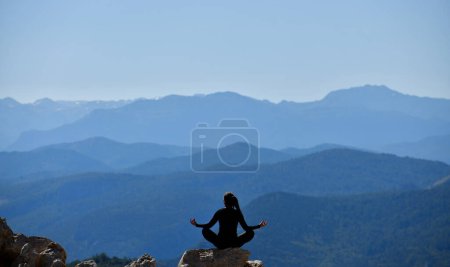 Téléchargez les photos : Silhouette d'une jeune femme pratiquant le yoga dans un paysage magnifique - en image libre de droit