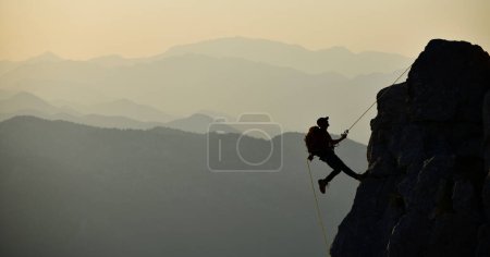 Photo for Climbing a Dangerous Rock with a Rope - Royalty Free Image