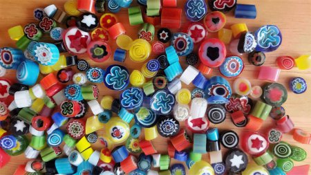 Dozens of round cuts of fusible glass multicolored cane with flower designs, retro millefiori