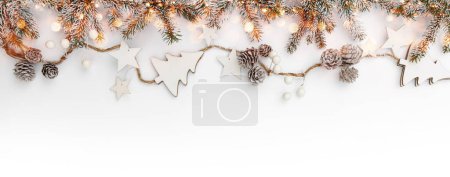 Foto de Guirnalda de Navidad feliz hecha de ramas de abeto nieve, conos, bayas, estrellas sobre fondo blanco con bokeh, destellos. Feliz Año Nuevo y Navidad, vista superior - Imagen libre de derechos
