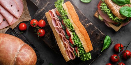 Photo for Delicious baguette sandwich with ham, bacon, cheese, lettuce, tomatoes, sausage, gammon on cutting board with herb and spices over on dark background. Meat food, top view, flat lay, toning - Royalty Free Image