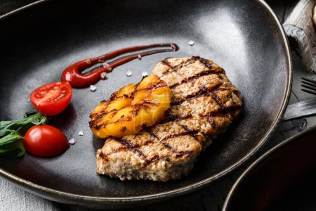 Photo for Grilled pork chop steak with tomatoes and spices on plate over rustic wooden background. Meat Dishes, top view, close up - Royalty Free Image