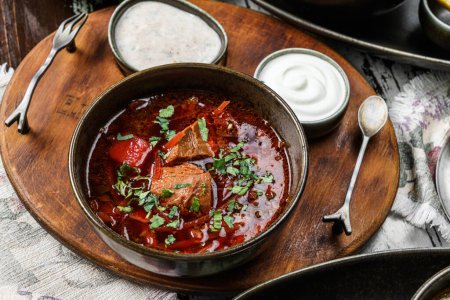 Photo for Ukrainian traditional beetroot soup - borscht in bowl with meat, rye bread and sour cream on bowl on rustic wooden background. Healthy food, top view - Royalty Free Image