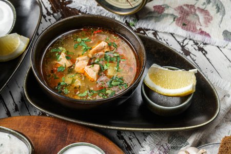 Foto de Sopa de pescado con salmón, verduras y limón en un bol sobre fondo rústico de madera. Comida saludable, vista superior - Imagen libre de derechos