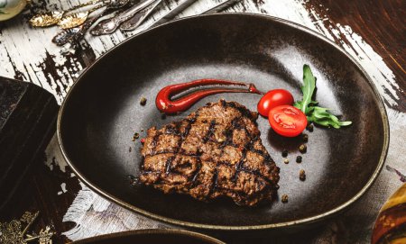 Photo for Grilled beef chop steak with tomatoes and spices on plate over rustic wooden background. Meat Dishes, top view, close up - Royalty Free Image