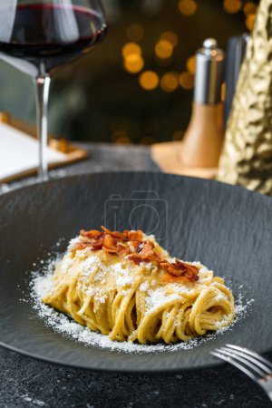 Photo for Delicious pasta with cheese parmesan on the table with glass of wine, background with bokeh, lights garland and glitter. Holiday dinner, Christmas food, close up, selective focus - Royalty Free Image