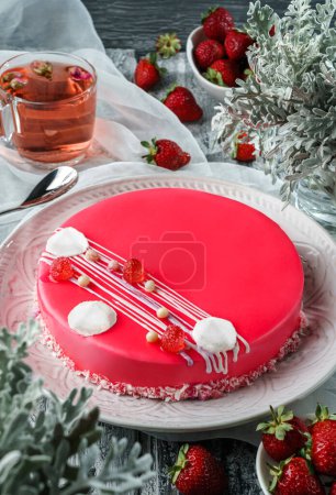 Foto de Pastel de mousse rosa con espejo vidriado, merengues y bayas sobre fondo claro con taza de té, fresas y flores. Dulces, postres y pasteles, vista superior - Imagen libre de derechos