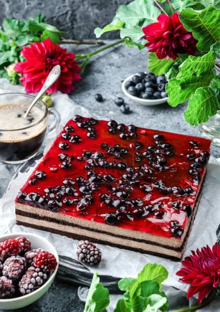 Photo for Chocolate mousse cake with berry jelly on grey background with cup of coffee, berries and red flowers. Sweets, dessert and pastry, top view - Royalty Free Image