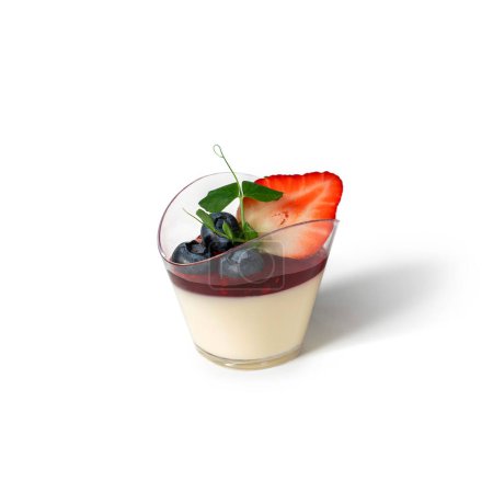 Téléchargez les photos : Délicieux pudding en mousse de panna cotta avec des baies dans une tasse en verre sur fond blanc. Candy bar, bonbons et desserts, focus sélectif - en image libre de droit