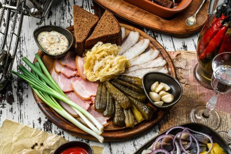 Photo for Sliced ham, bacon, lard, pickles, green onions, slices of rye bread on cutting board over rustic background. Appetizer for vodka, top view - Royalty Free Image