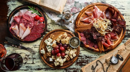 Photo for Snacks and Wine appetizer sets, cold meat plates with sausage, ham, salami, prosciutto, bacon and cheese plate with parmesan, blue cheese, brie cheese, cheddar on background. Top view - Royalty Free Image