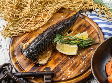 Foto de Pescado de caballa ahumado con limón y romero sobre tabla de cortar sobre fondo rústico de madera. Mariscos, comida saludable, vista superior - Imagen libre de derechos