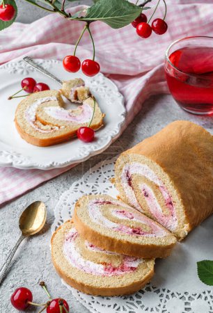 Photo for Delicious sponge roll cake stuffed with cream and cherries on napkin on light background with cherry branch with berries. Sweets, dessert and pastry, close up, selective focus - Royalty Free Image