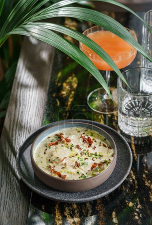 Foto de Deliciosa sopa de crema con tomates secos y micro verduras en un tazón sobre una mesa de mármol con batidos. Comida saludable, vista superior - Imagen libre de derechos