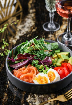 Photo for Buddha bowl salad with salmon fish, arugula, spinach, avocado, tomatoes, green edamame beans, eggs on marble background. Healthy salad, dieting, top view, close up - Royalty Free Image