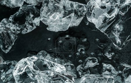 Téléchargez les photos : Des morceaux de glace écrasée sur fond noir. Fond abstrait de la structure de glace, vue de dessus - en image libre de droit