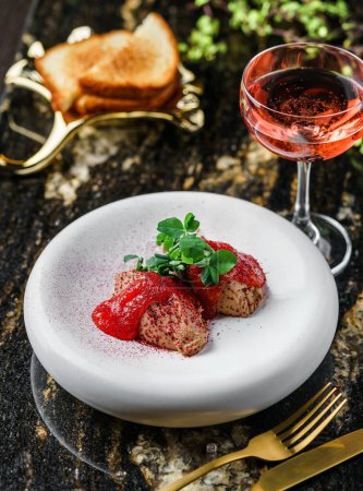 Delicious meat pate foie gras on plate with berry sauce, sprouts and toasts on marble background with drinks. Healthy food, top view