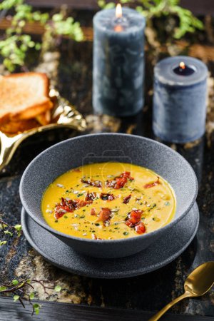 Photo for Tasty lentil cream soup with seeds, tomatoes, croutons in bowl on marble background with candles and flowers. Healthy food, top view - Royalty Free Image