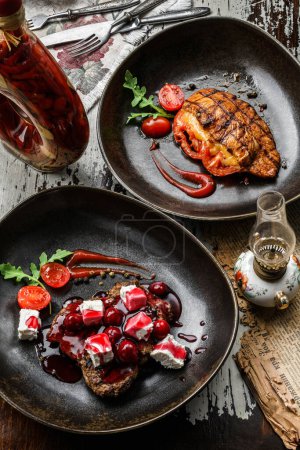 Photo for Grilled meat chop steaks with berries sauce, cheese and tomatoes on plate on wooden background. Meat Dishes, top view - Royalty Free Image