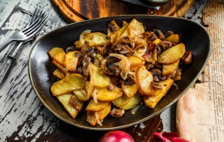Photo for Fried homemade potatoes with mushrooms on plate on wooden background, top view - Royalty Free Image