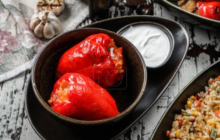 Photo for Stuffed bell peppers with sour cream in plate on wooden background. Homemade food, top view - Royalty Free Image