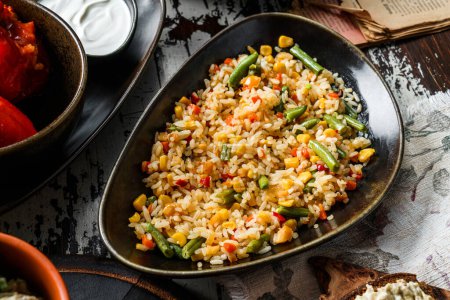 Foto de Delicioso arroz con verduras, frijol francés, maíz en plato sobre fondo de madera. Comida vegetariana, vista superior, primer plano - Imagen libre de derechos