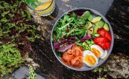 Photo for Buddha bowl salad with salmon fish, arugula, spinach, avocado, tomatoes, green edamame beans, eggs on marble background. Healthy salad, dieting, top view - Royalty Free Image