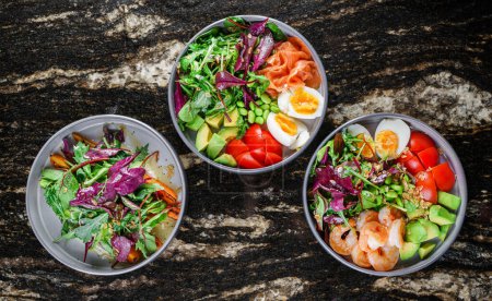 Photo for Buddha bowls with salads with shrimps and salmon fish ,arugula, spinach, avocado, tomatoes, green edamame beans, eggs on marble background. Healthy salad food, dieting, top view - Royalty Free Image
