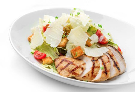 Téléchargez les photos : Salade César avec poitrine de poulet grillée, tomates cerises, croûtons, fromage parmesan, laitue dans une assiette isolée sur fond blanc. Alimentation saine, vue de dessus - en image libre de droit