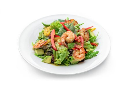 Téléchargez les photos : Salade fraîche saine aux crevettes, avocat, laitue, épinards, sésame, poivron et sauce dans une assiette isolée sur fond blanc. Alimentation saine, vue de dessus - en image libre de droit