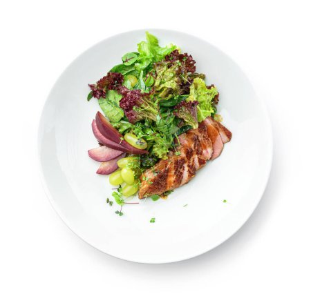 Téléchargez les photos : Salade saine avec steak de bœuf, poire, raisin, laitue, roquette et sauce dans une assiette isolée sur fond blanc. Alimentation saine, vue de dessus - en image libre de droit