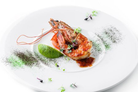 Téléchargez les photos : Grandes crevettes tigrées grillées à la lime, microgreens et sauce dans une assiette isolée sur fond blanc. Fruits de mer sains, vue de dessus - en image libre de droit