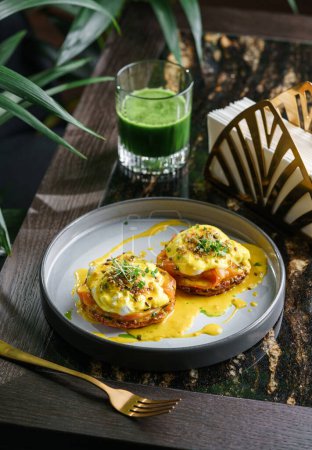 Photo for Delicious pancake with slice of salmon, eggs Benedict or poached eggs and sesame and microgreens on plate on marble table with smoothie. Healthy breakfast food, diet, top view - Royalty Free Image