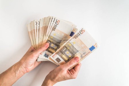 Foto de Manos femeninas sosteniendo billetes en euros aislados sobre fondo blanco. Efectivo europeo con billetes de 50 euros, vista superior - Imagen libre de derechos