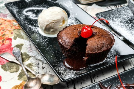 Pastel de fondant de chocolate con helado y cerezas en plato sobre fondo de madera. Dulces, postres y pasteles, primer plano
