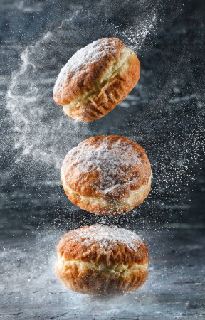 Téléchargez les photos : Three delicious Donuts with custard and powdered sugar frozen in motion on grey stone background. Sweets, dessert and pastry, close up - en image libre de droit