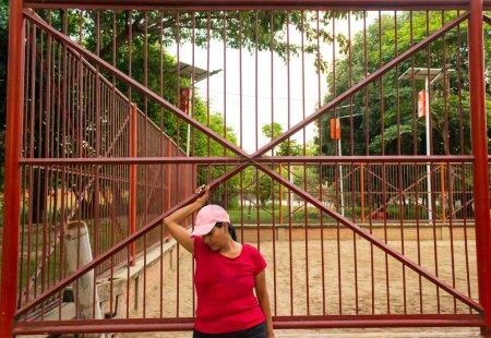 Téléchargez les photos : Tristesse en latin brunette femme saisir une clôture - en image libre de droit