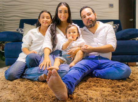 Schöne Latino-Familie sitzt auf einem Teppich