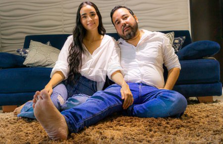 Colombian Latin couple sitting on a brown rug in their home