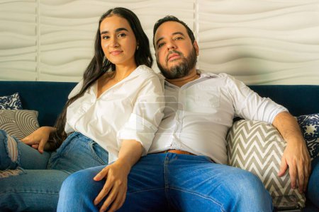 Pareja latina colombiana sentada en un sofá azul