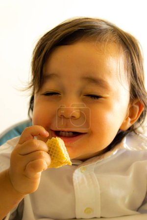 Beau petit garçon exprime l'excitation sur son visage quand il mange un cookie