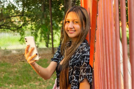 Mujer joven latina con smartphone en la mano derecha en el parque