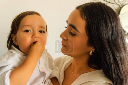 Latina mamá sosteniendo a su hijo en sus brazos mientras él come una galleta