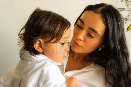 Latina mère parle avec amour à son bébé fils tout en le tenant dans ses bras